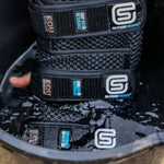 Stack of black EQU STREAMZ cool boots in bucket of cold water for cooling